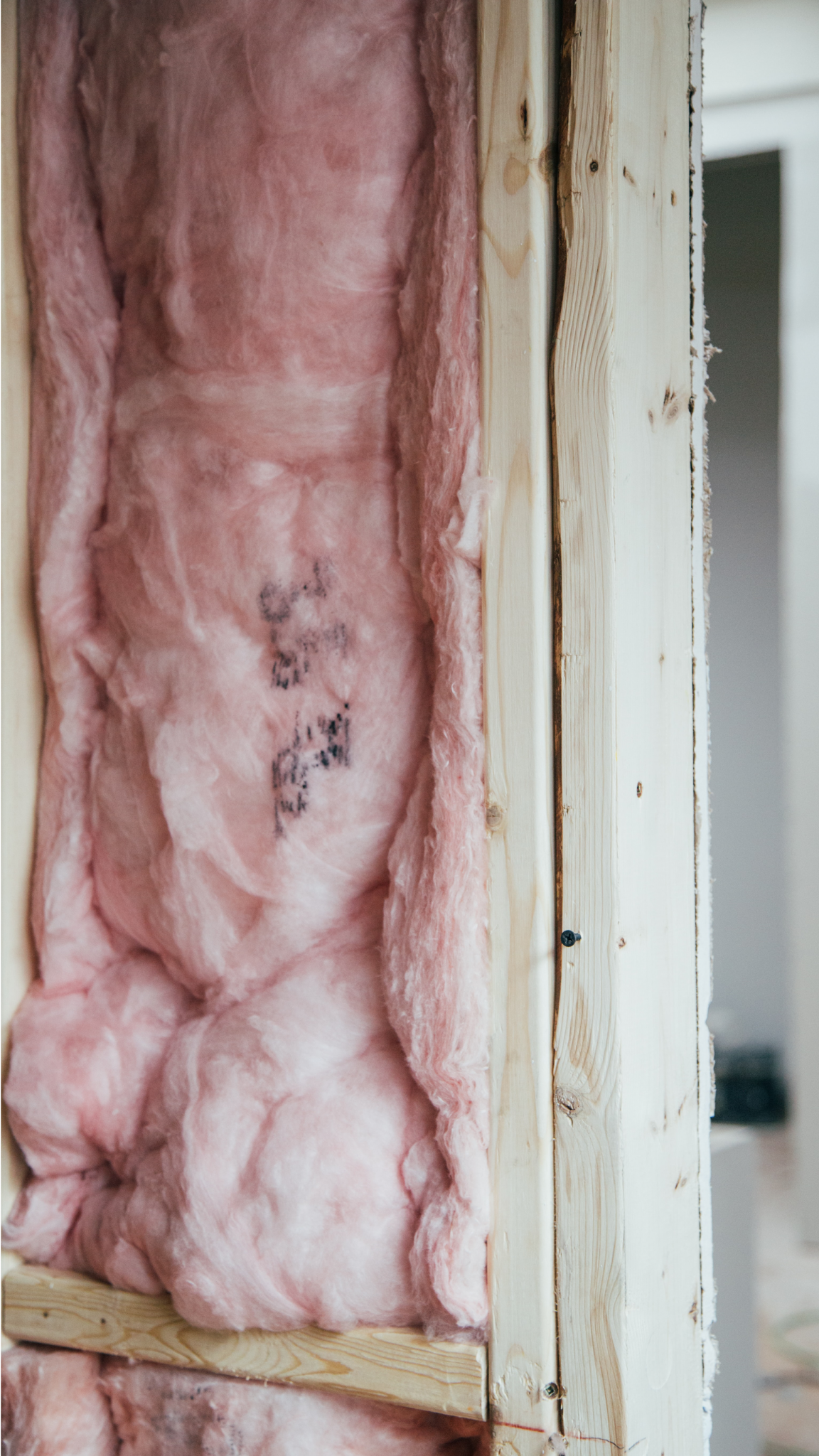 Une isolation en fibre de verre rose remplit une ossature murale en bois. Gros plan montrant la texture et les détails de l'isolation.