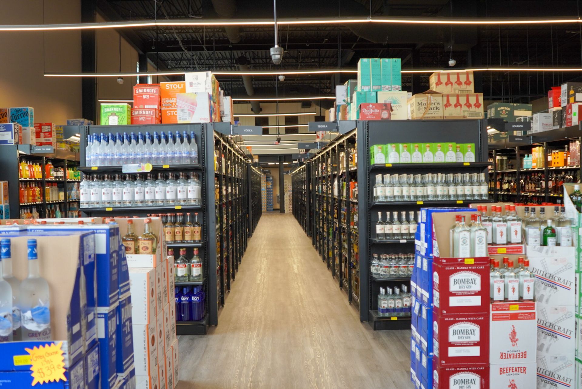 A long aisle of a liquor store filled with lots of bottles and boxes.