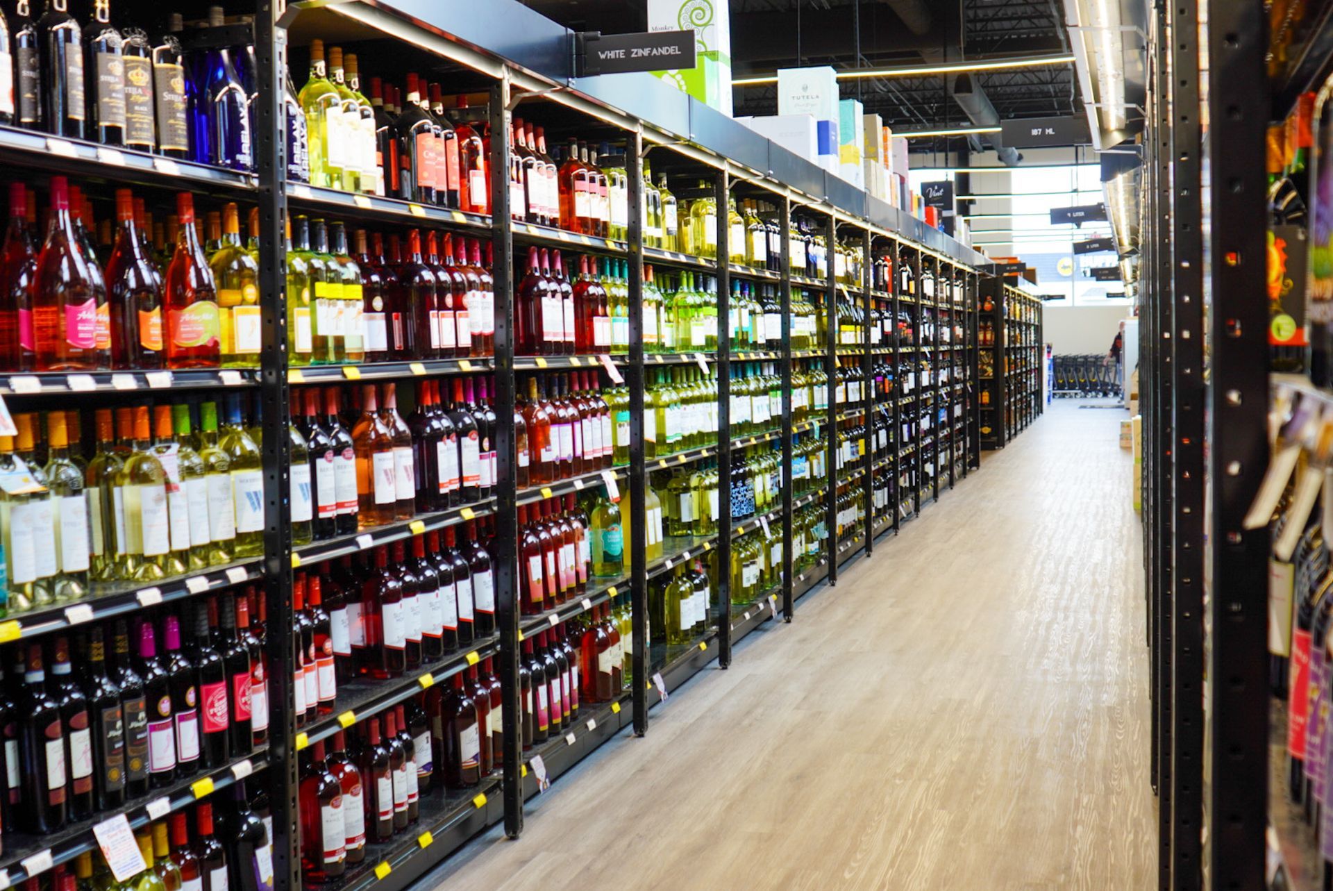 A row of shelves filled with bottles of wine in a grocery store.