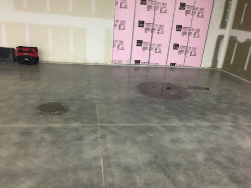 A concrete floor in a garage with pink insulation on the walls.
