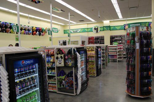 The inside of a store with a pepsi refrigerator in the middle.