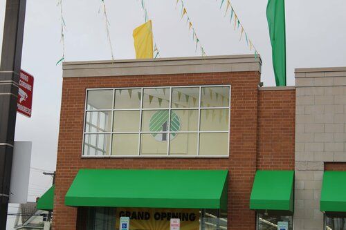 A brick building with green awnings and a sign that says grand opening
