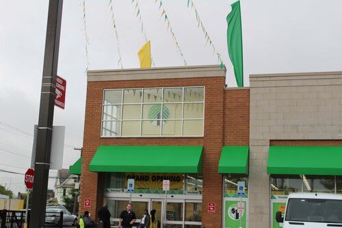 A store with a green awning and a sign that says grand opening