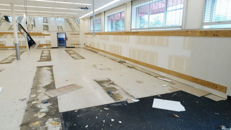 A large empty room with a lot of windows and a black mat on the floor.