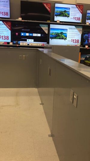 A row of televisions are lined up on a shelf in a store.