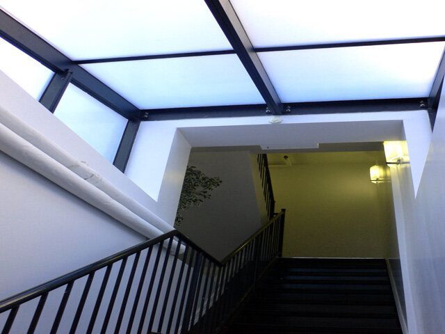 A staircase with a railing and a skylight above it