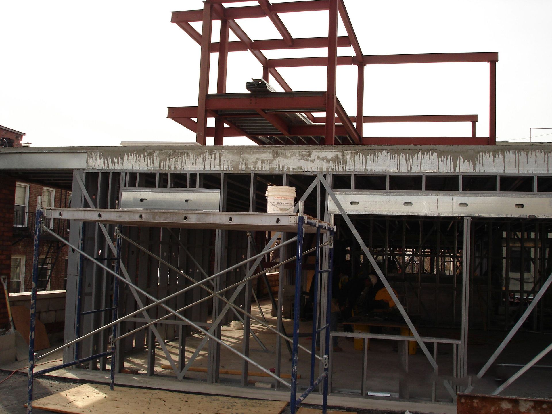 A building under construction with scaffolding and a bucket of water