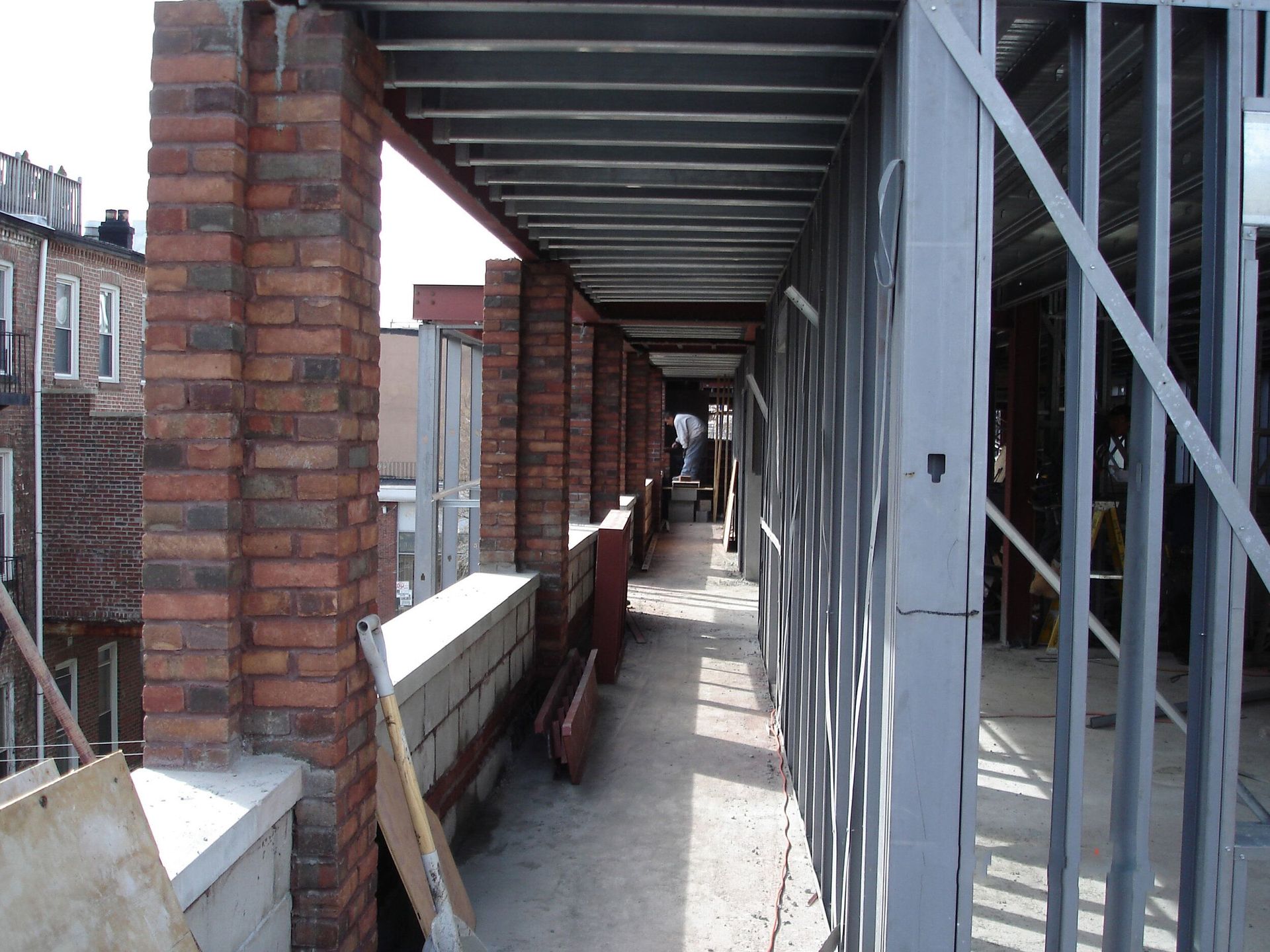 A long hallway with brick columns and a metal fence