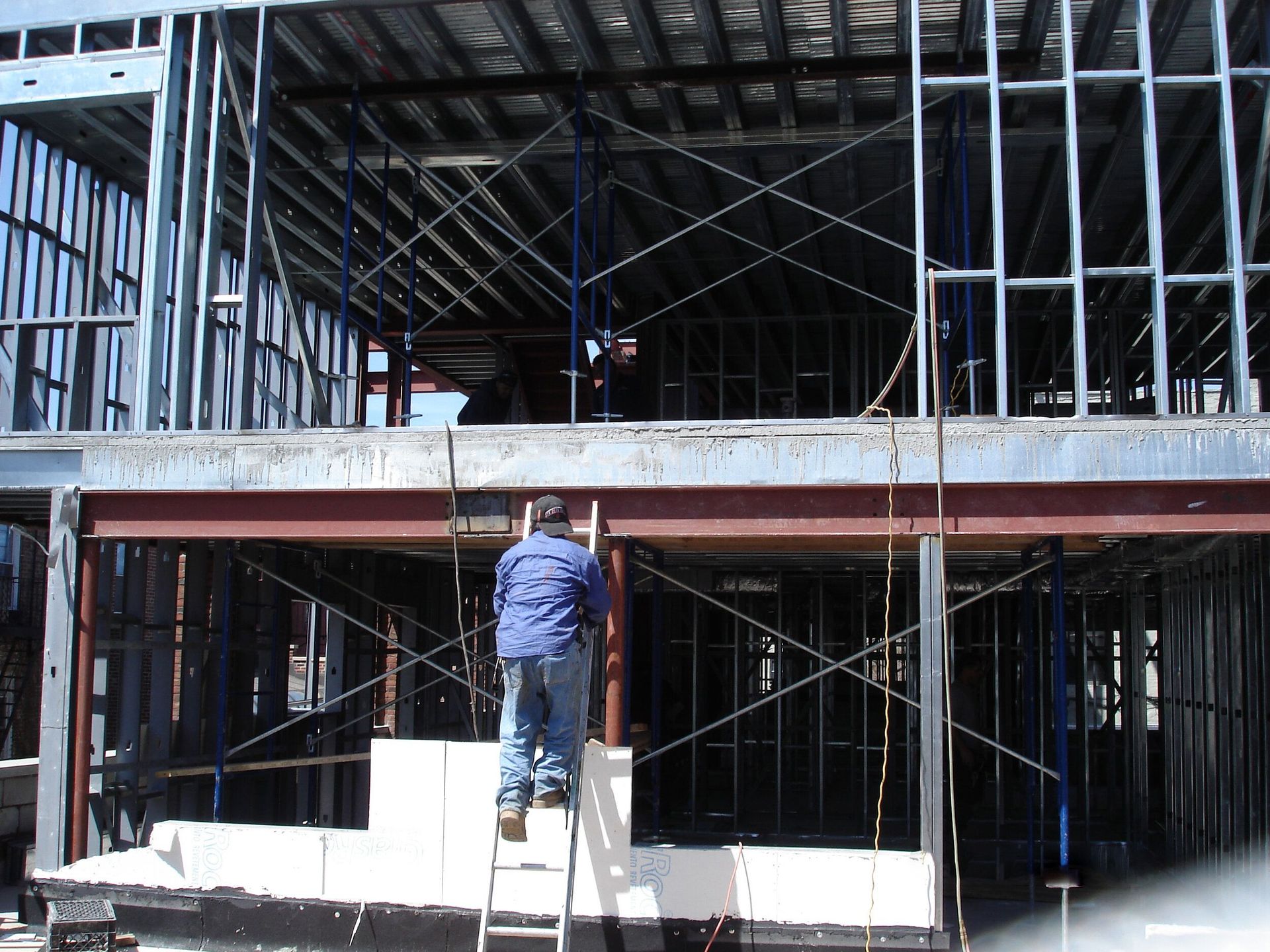 A man is standing on a ladder in front of a building under construction