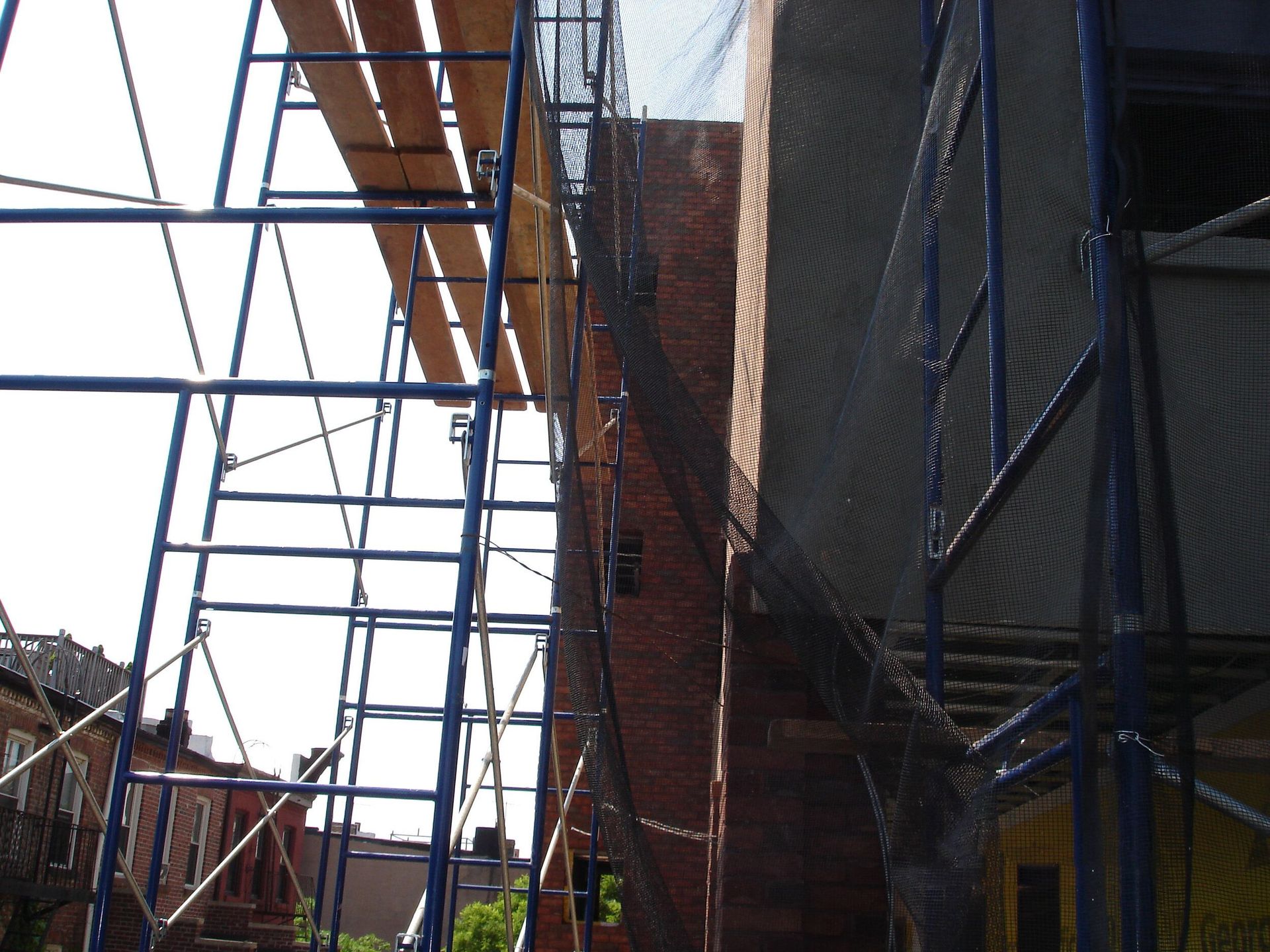 A brick building with a blue scaffolding in front of it