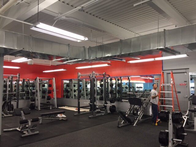 A man is standing in a gym with a red wall