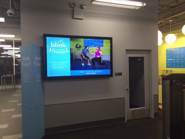 A blink fitness screen is hanging on a wall