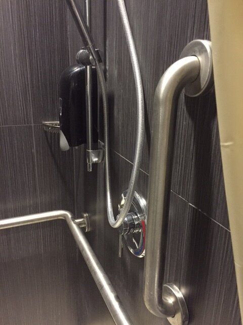 A bathroom with a shower and a hand sanitizer dispenser.