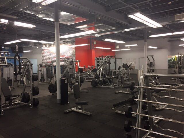 A gym with a lot of equipment and a red wall