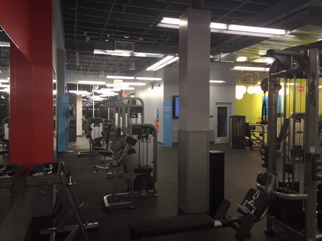 A gym with a lot of equipment and a red wall
