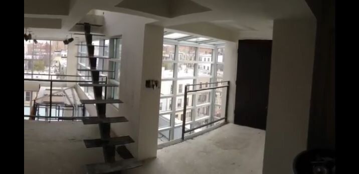 An empty room with a spiral staircase and a balcony