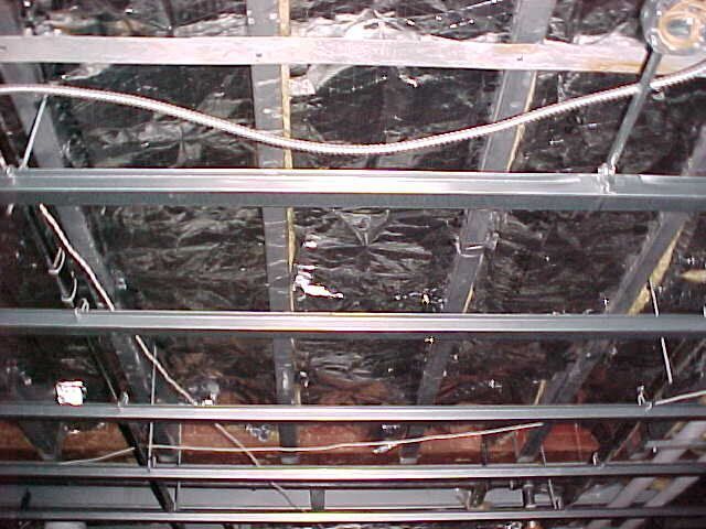 The ceiling of a building with a lot of wires hanging from it.