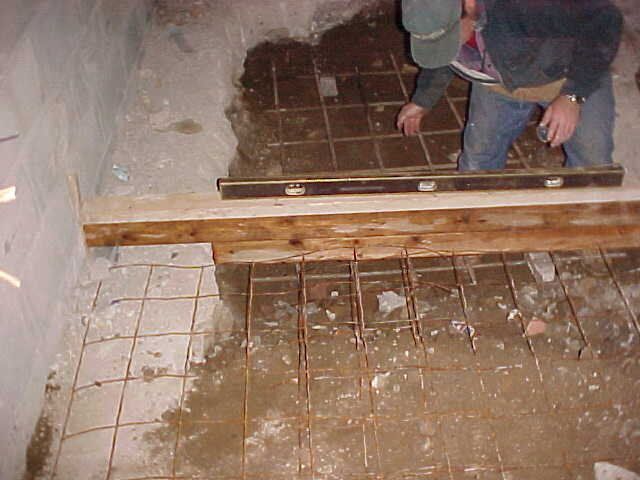 A man is leveling a concrete floor with a level.