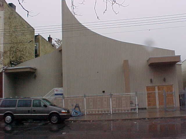 A van is parked in front of a church on a rainy day