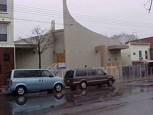 Two vans are parked in front of a building on a rainy day