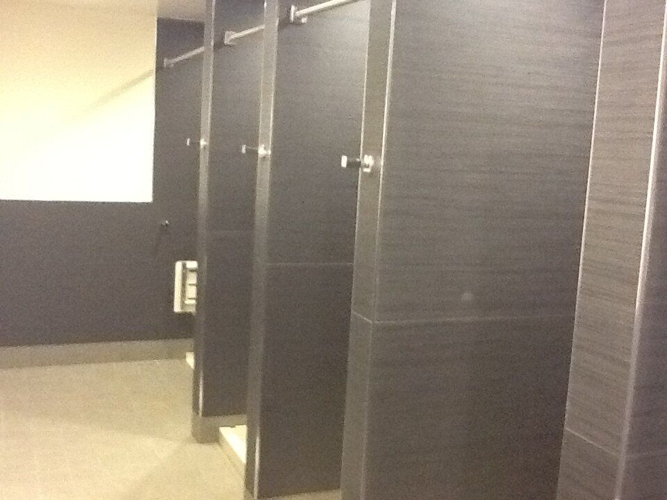 A row of black cubicles in a public restroom