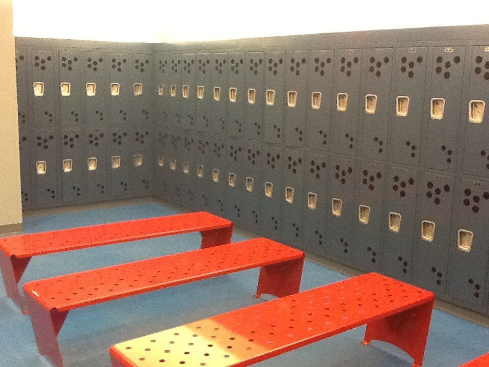 A row of red benches in front of a wall of lockers