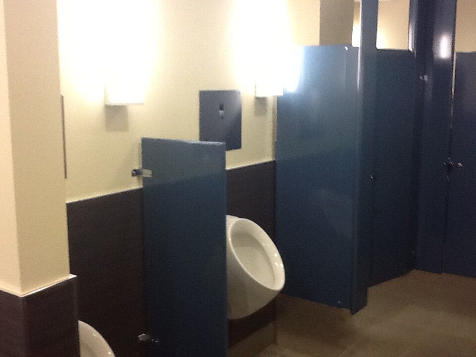 A public restroom with a urinal between two stalls