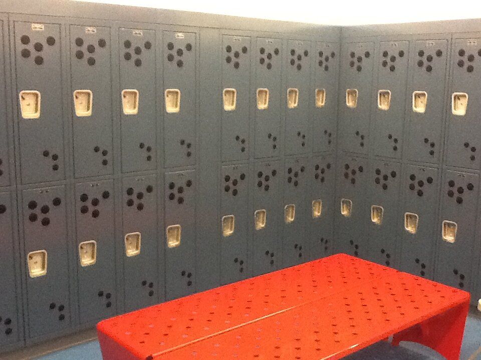 A locker room with lots of lockers and a red table