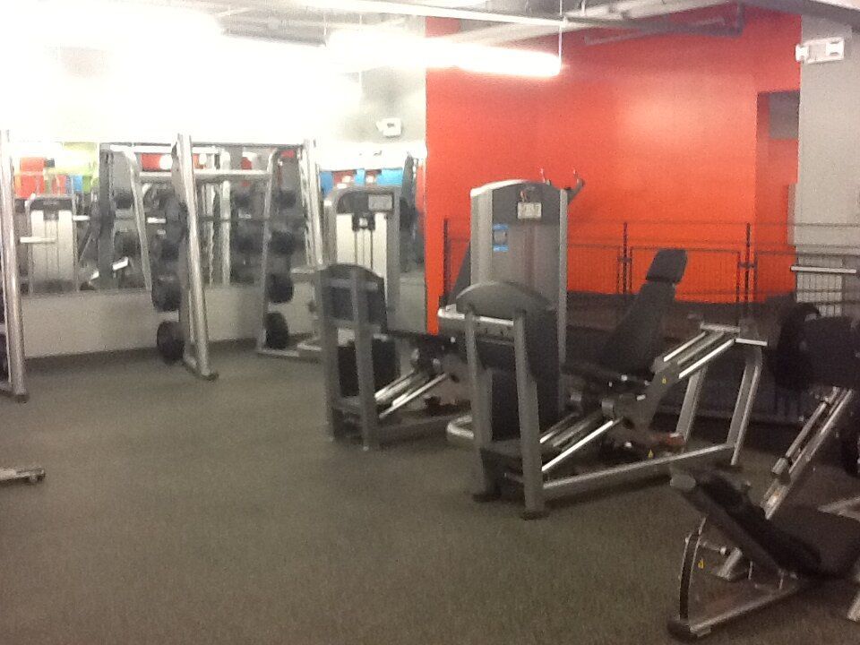A gym with a lot of equipment and a red wall
