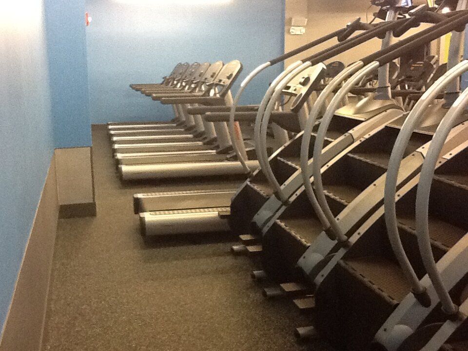 A row of treadmills and stairs in a gym