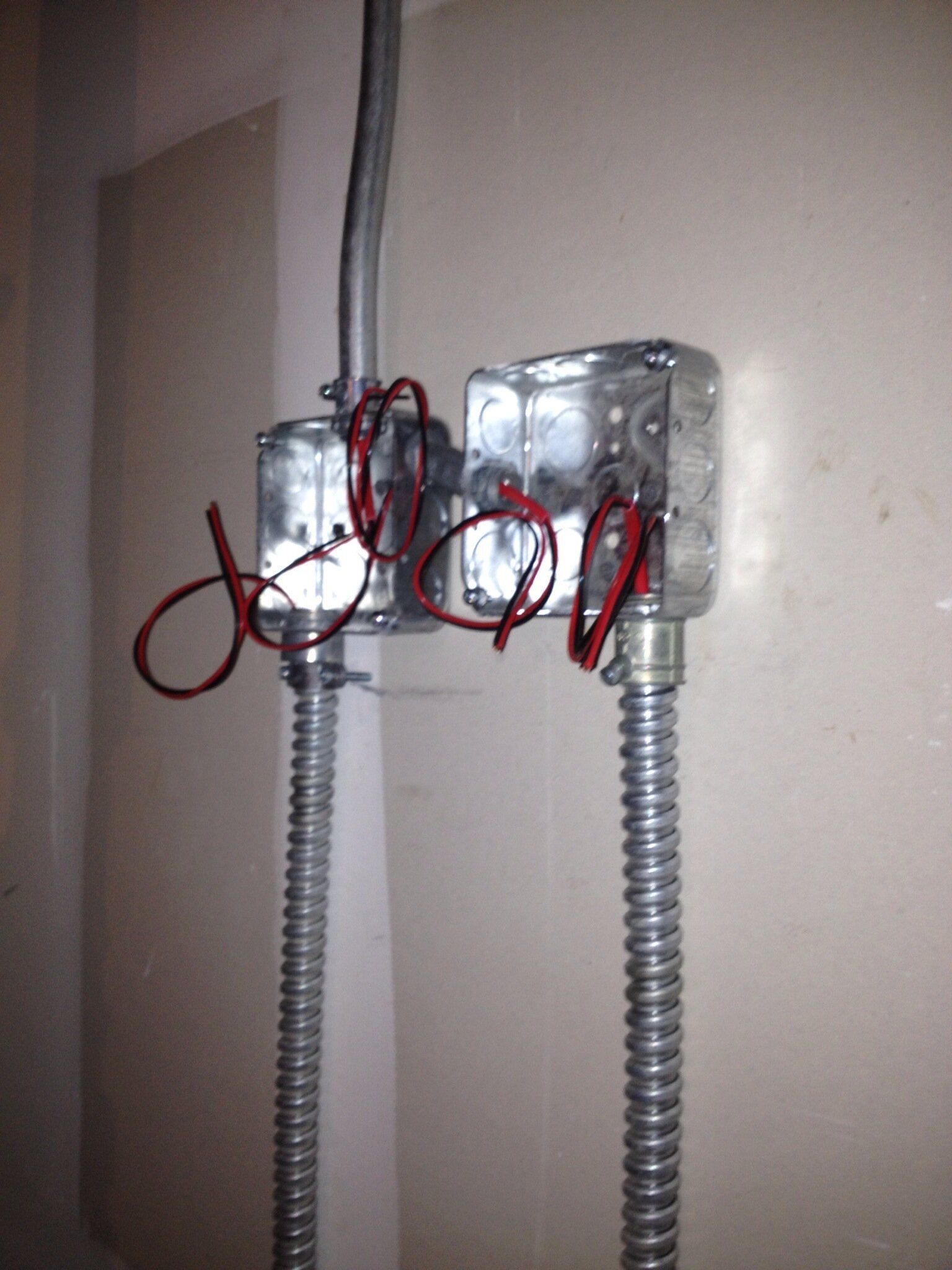 Two electrical boxes with red wires attached to them