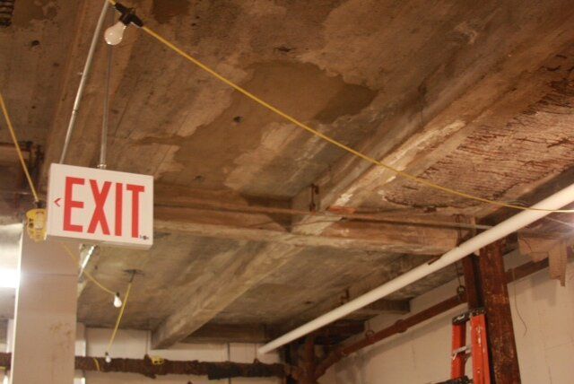 An exit sign hangs from the ceiling of a building