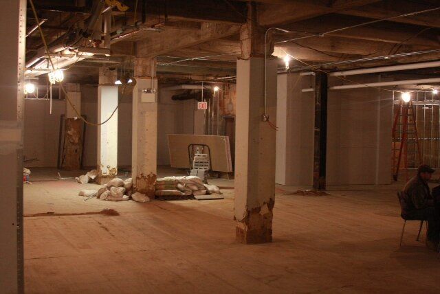 A man is sitting on a bench in an empty basement.