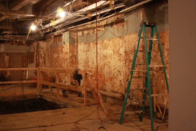 A ladder is sitting in a room with a hole in the floor.