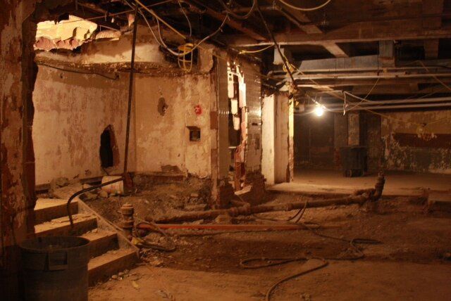 An empty basement with a lot of wires hanging from the ceiling.