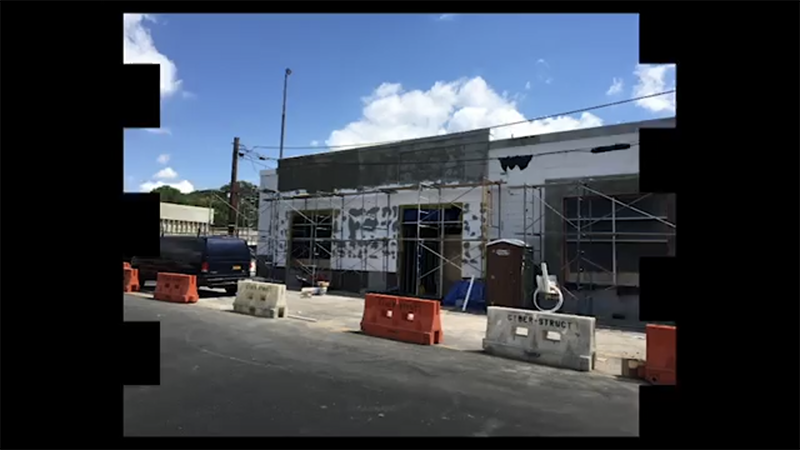 A picture of a building under construction with scaffolding and orange barriers.