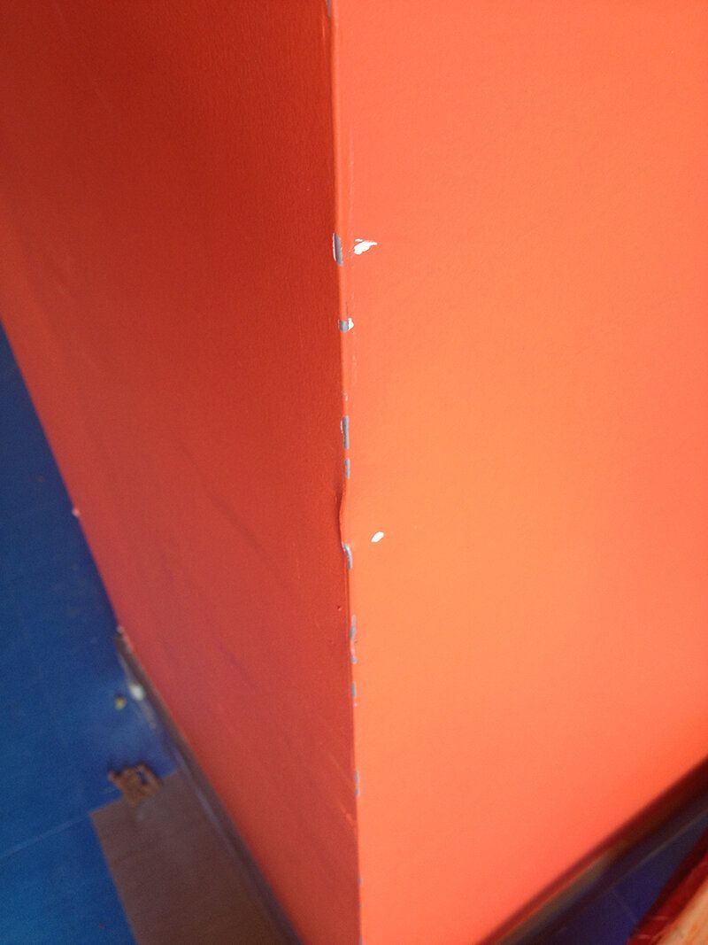 A close up of a red wall with a blue floor in the background.