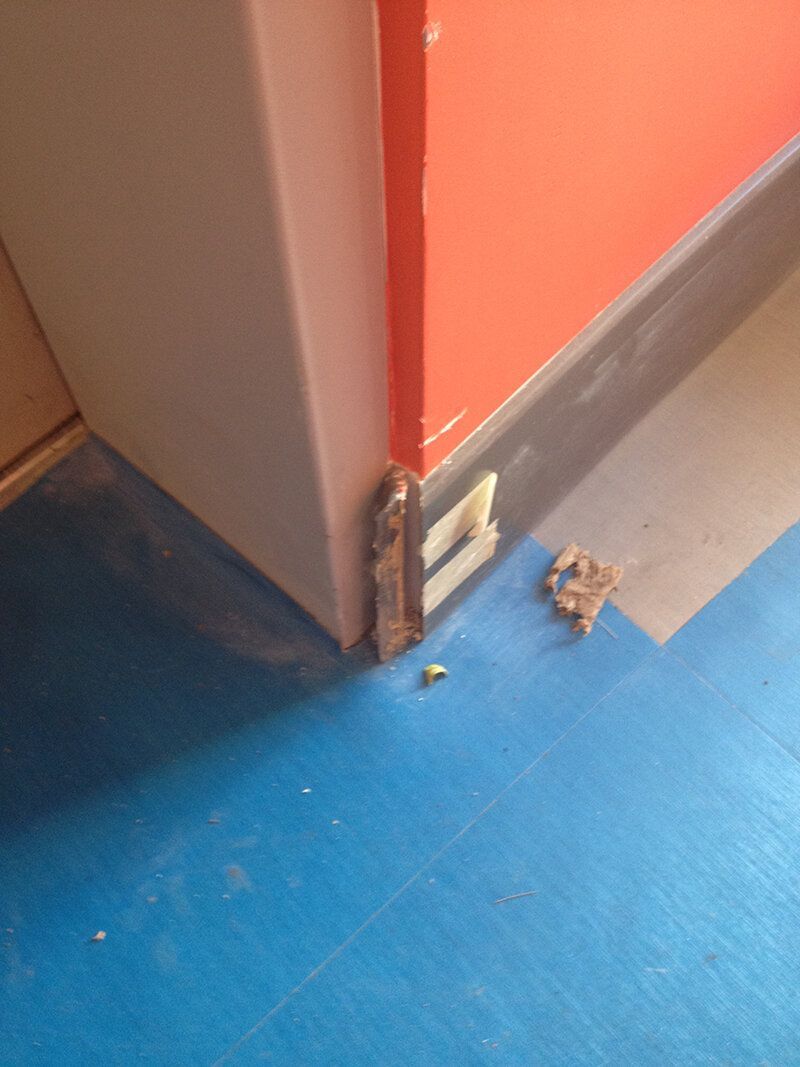 A corner of a room with a blue floor and a red wall.