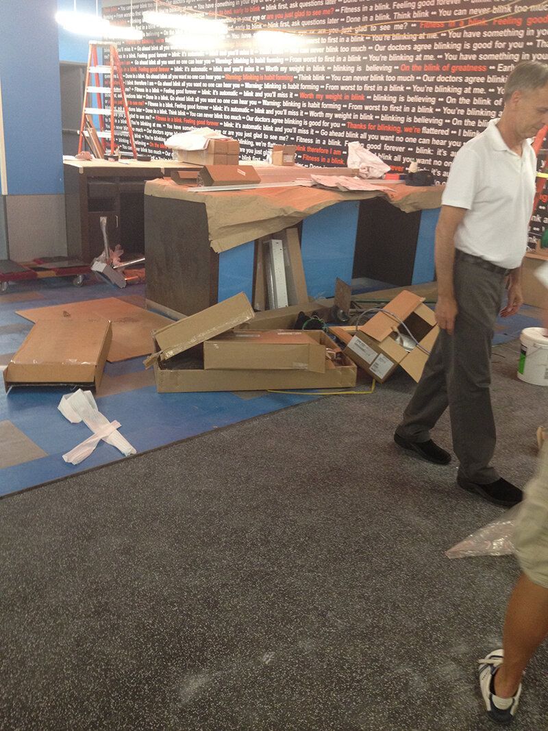 A man in a white shirt is walking through a messy room