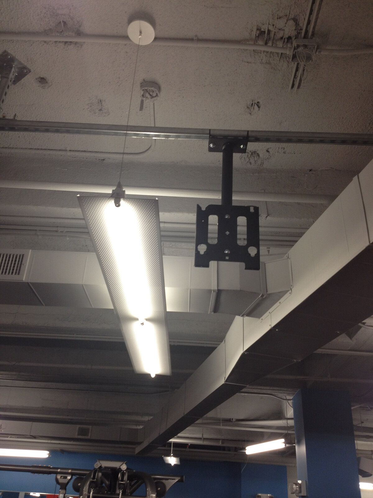 A tv mount is hanging from the ceiling of a building