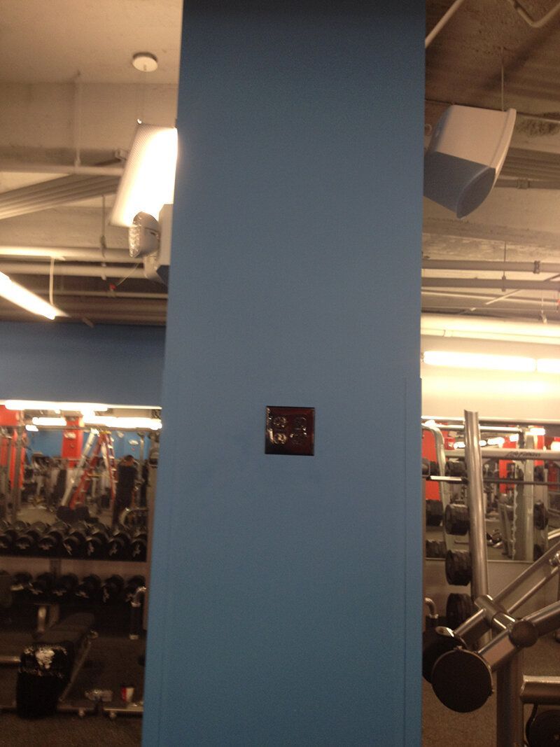 A blue wall in a gym with a clock on it