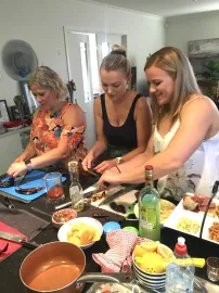 Three women are preparing food on a counter in a kitchen.