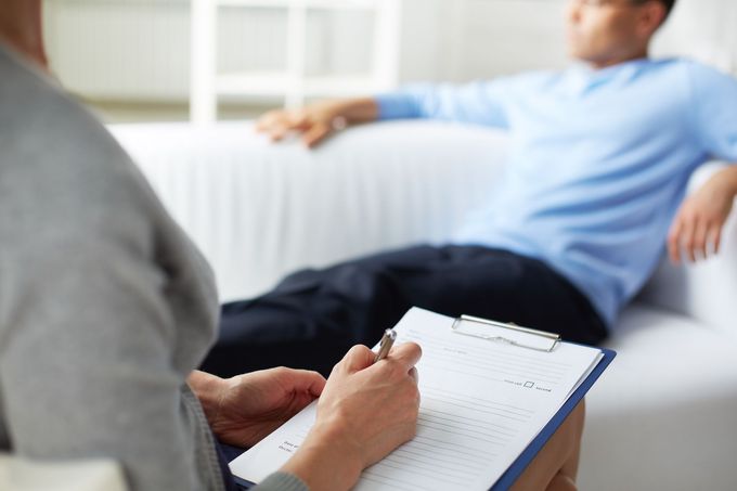 Il terapeuta prende appunti mentre il paziente è seduto su un divano durante una seduta di consulenza.