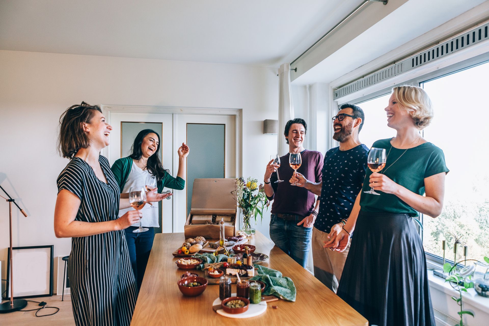a group of people are standing around a table holding wine glasses .