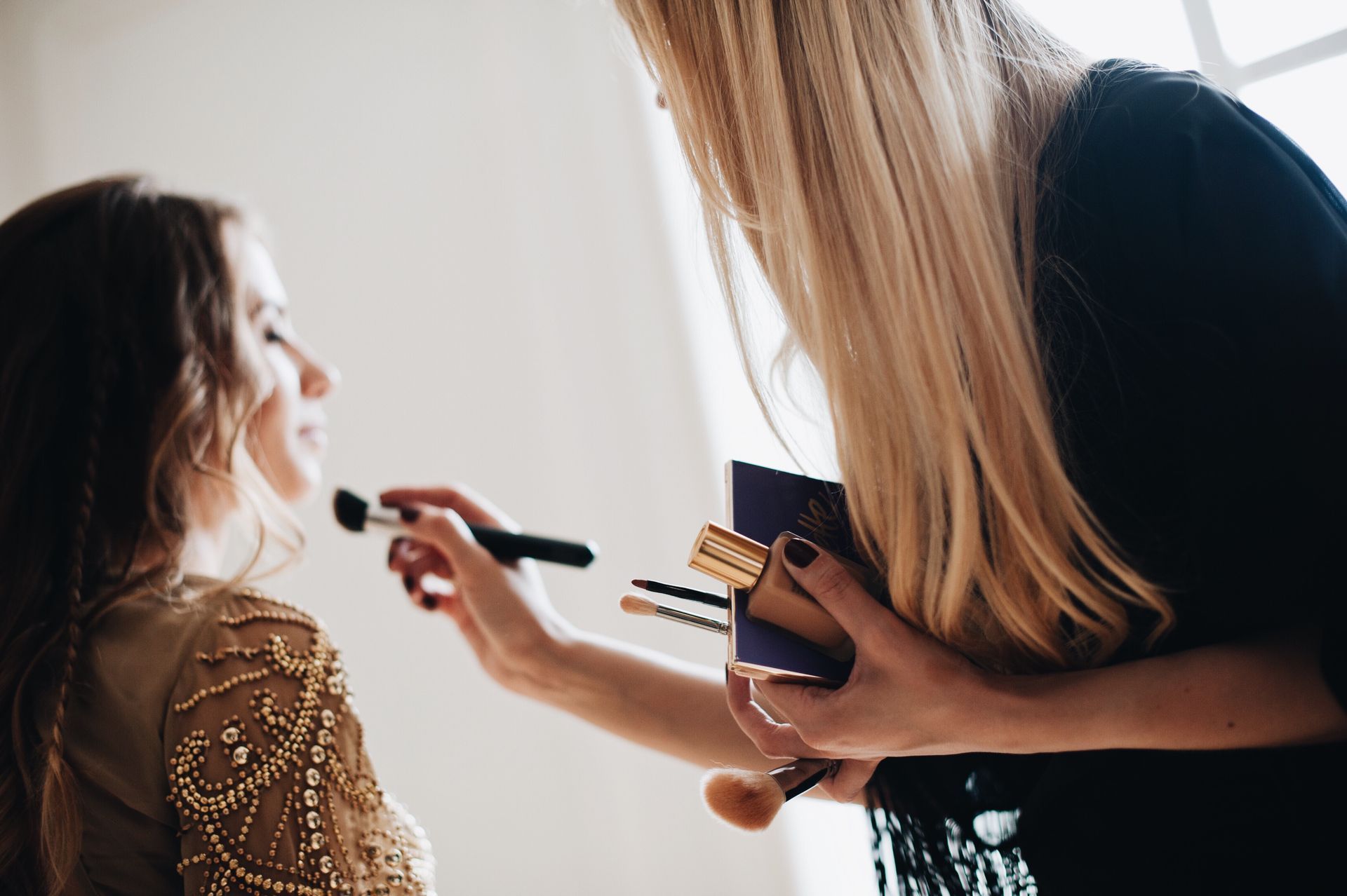 a woman is applying makeup to another woman 's face .