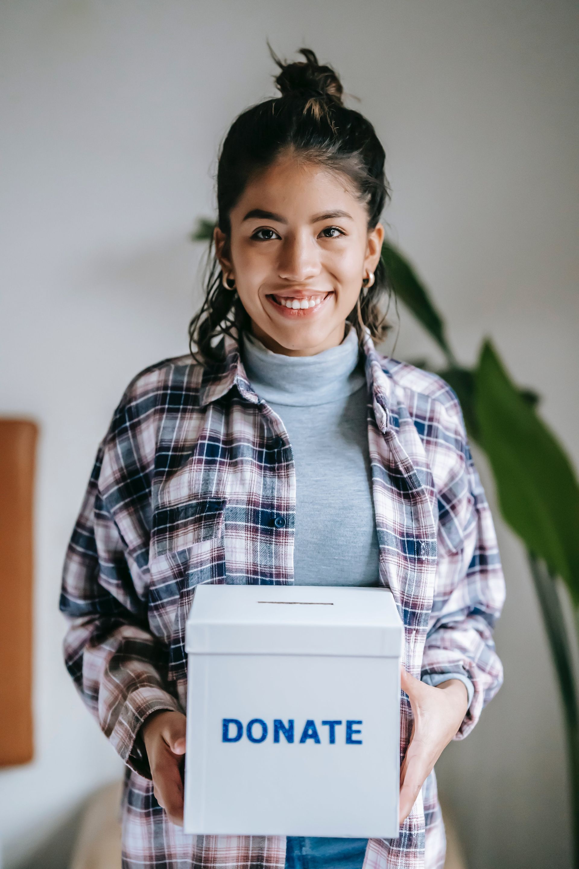 a woman is holding a donate box in her hands .