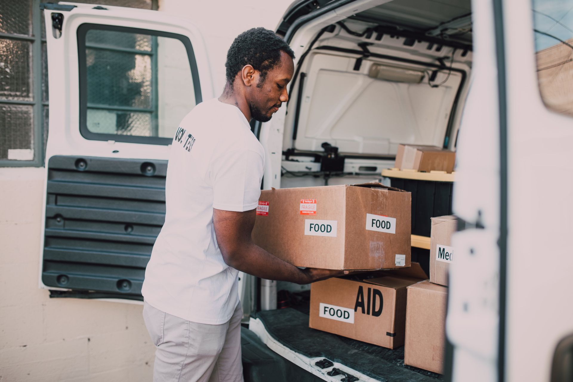 a man is loading boxes into the back of a van .