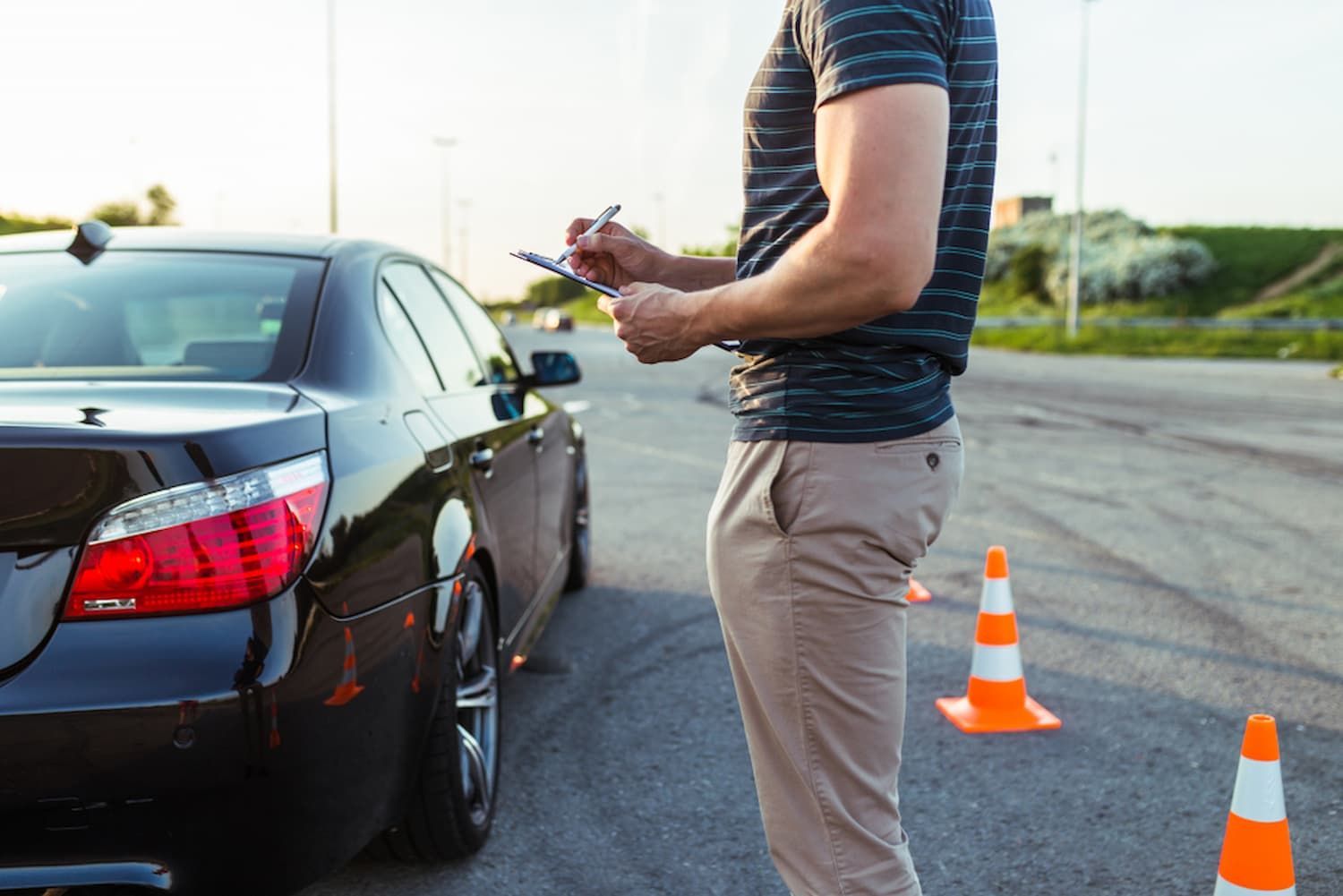 A Man Is Standing in Front of A Car and Writing on A Piece of Paper — R.P's Total Assessments & Driver Training Pty Ltd In Stanthorpe, QLD