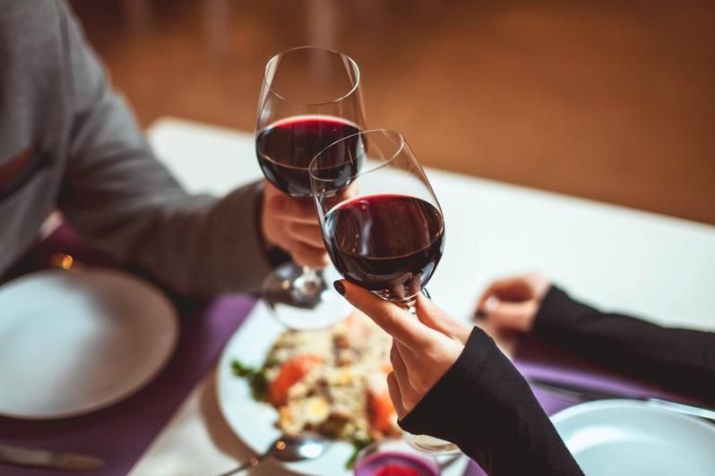 Um homem e uma mulher estão brindando com taças de vinho em um restaurante.