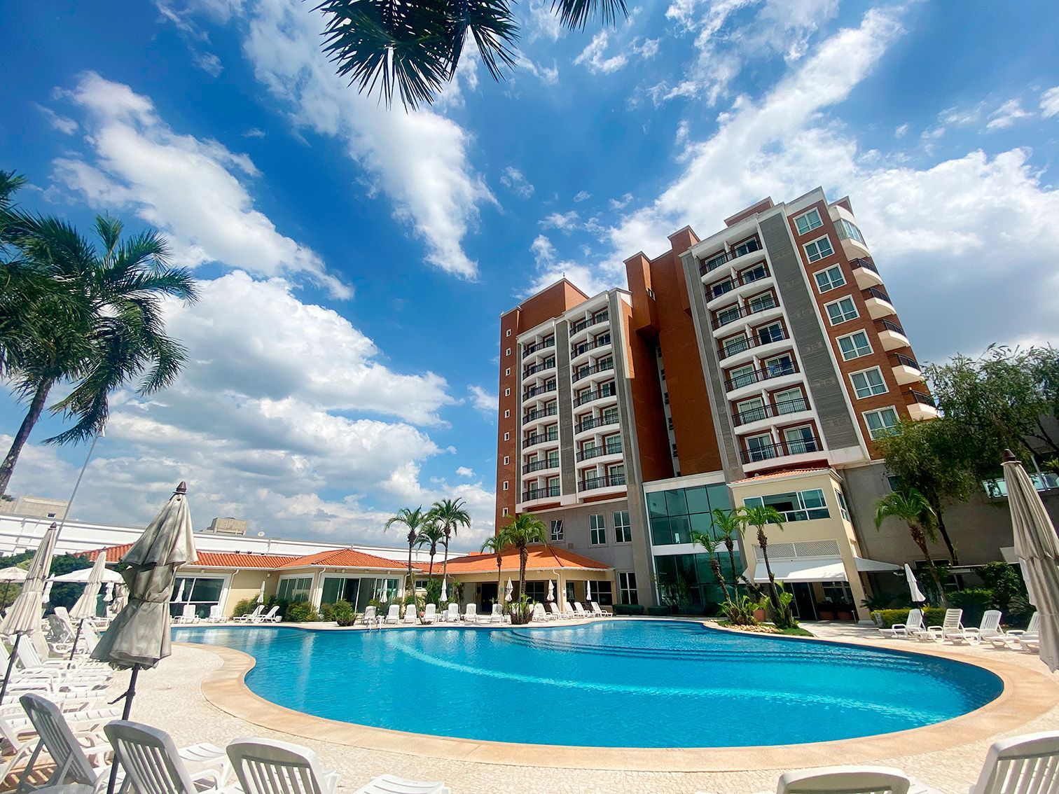 Há uma grande piscina em frente a um hotel.